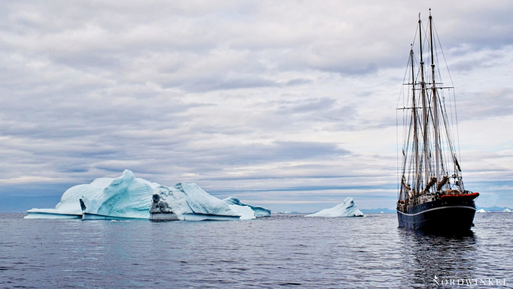 Segelschiff zwischen großen Eisbergen