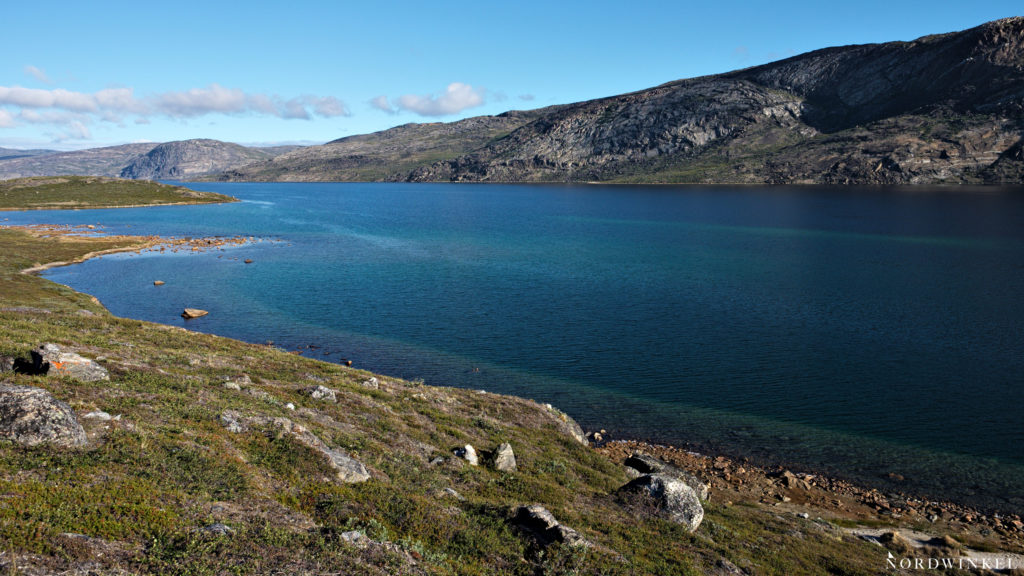 lake amitsorsuaq under blue sky with green-blue water at the arctic circle trail