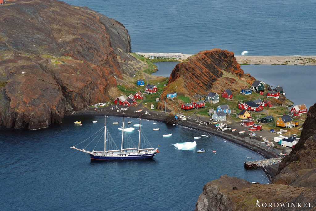 ankerndes segelschiff vor einer grönländischen siedlung