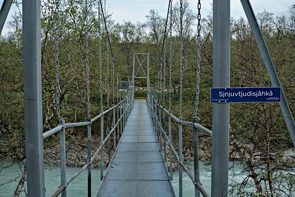 metallene hängebrücke über einen türkisen fluss